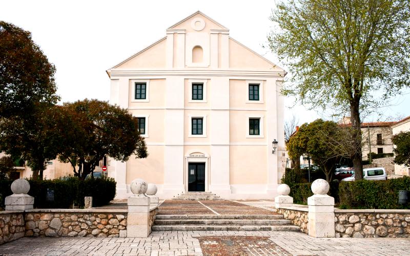 The facade of a white house with trees on both sides